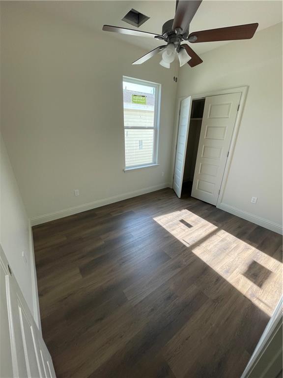 unfurnished bedroom featuring ceiling fan, dark hardwood / wood-style floors, lofted ceiling, and a closet