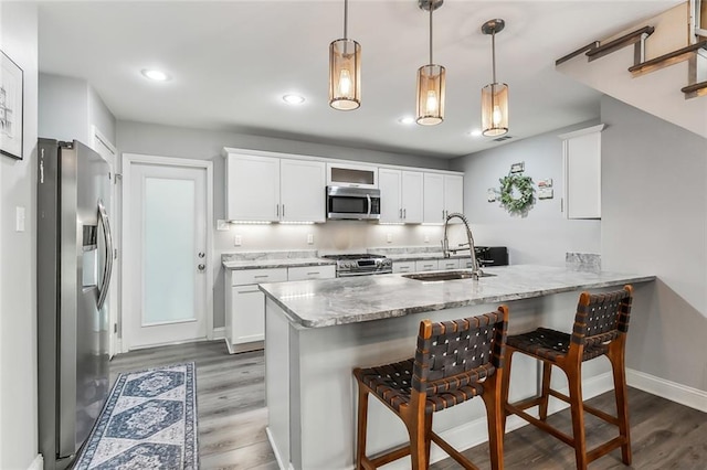 kitchen with white cabinets, light stone countertops, decorative light fixtures, kitchen peninsula, and stainless steel appliances