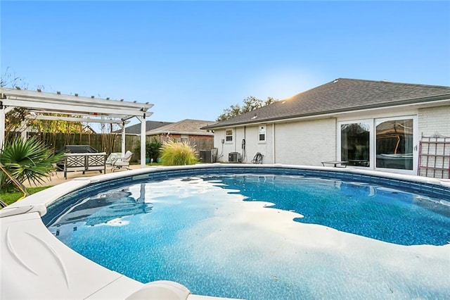 view of swimming pool with central AC unit and a pergola