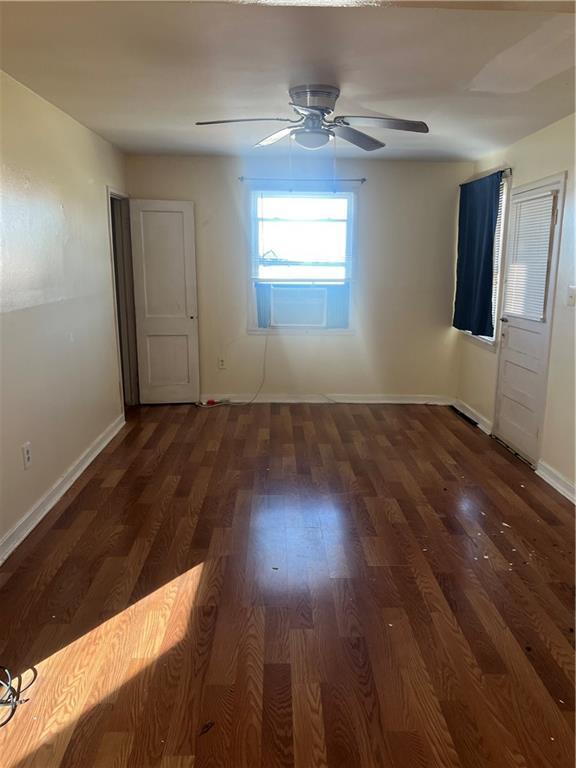 unfurnished room with dark hardwood / wood-style floors, ceiling fan, and cooling unit