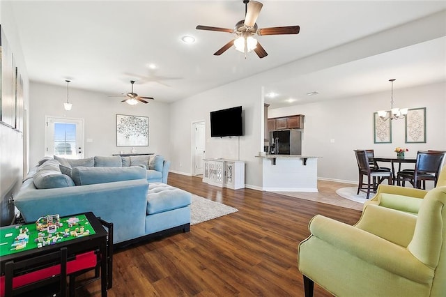 living room with ceiling fan with notable chandelier and dark hardwood / wood-style flooring