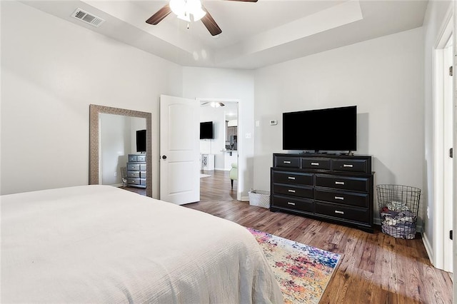 bedroom featuring a tray ceiling, ceiling fan, and dark hardwood / wood-style floors