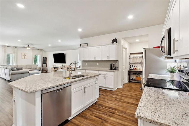 kitchen featuring a kitchen island with sink, appliances with stainless steel finishes, light stone counters, sink, and white cabinetry