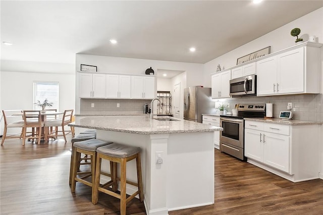 kitchen featuring stainless steel appliances, white cabinetry, an island with sink, and sink