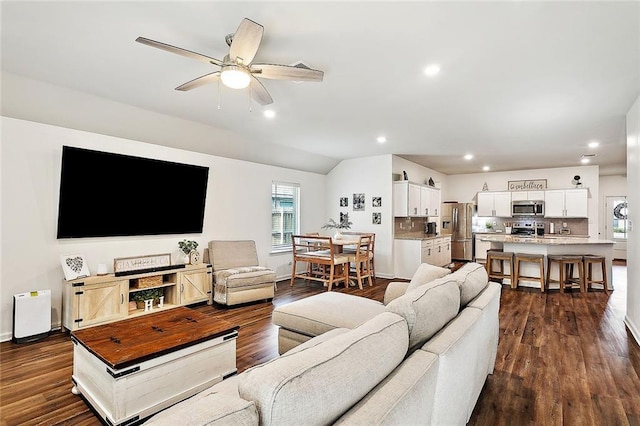 living room featuring dark hardwood / wood-style flooring, ceiling fan, vaulted ceiling, and a wealth of natural light