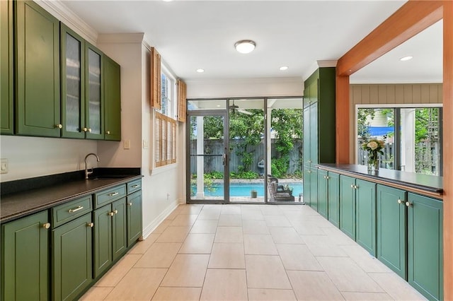 interior space with sink, green cabinets, crown molding, and light tile patterned flooring