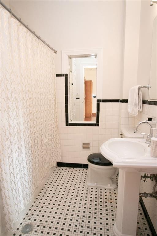 bathroom featuring curtained shower, toilet, tile patterned flooring, and tile walls