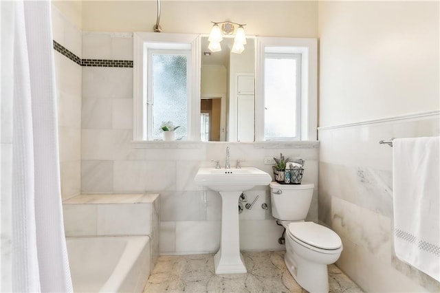 bathroom featuring toilet, tile walls, and a bathing tub