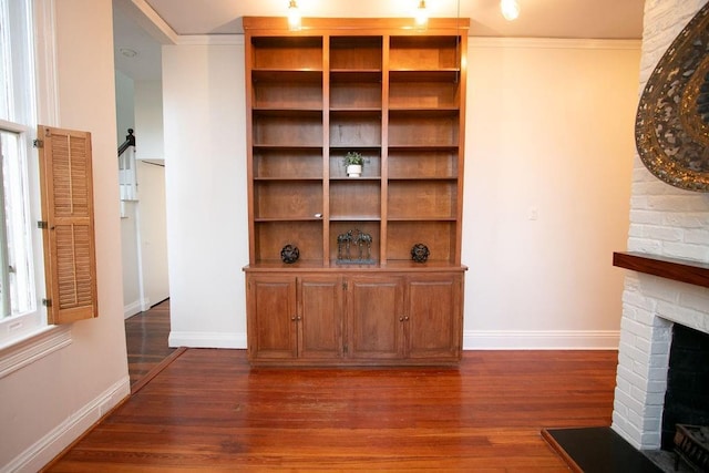 living room with a brick fireplace, crown molding, and dark hardwood / wood-style floors