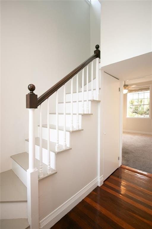 staircase featuring ceiling fan, a high ceiling, and hardwood / wood-style floors