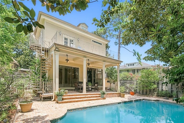 back of property with a balcony, a fenced in pool, a patio area, and ceiling fan