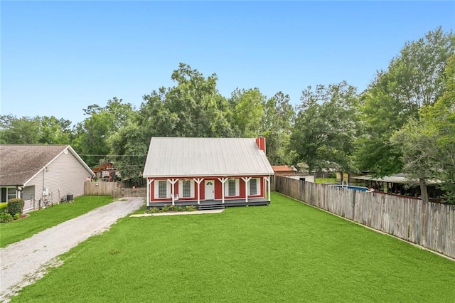 view of front facade featuring gravel driveway, covered porch, a front lawn, and fence