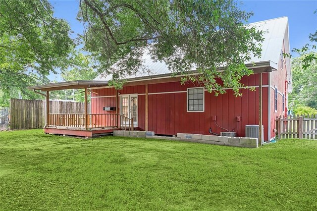 back of house featuring a deck, central AC unit, fence, and a lawn