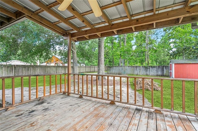 wooden terrace with an outbuilding, a yard, a fenced backyard, and a storage unit