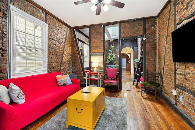 interior space with ceiling fan, wood-type flooring, crown molding, and brick wall