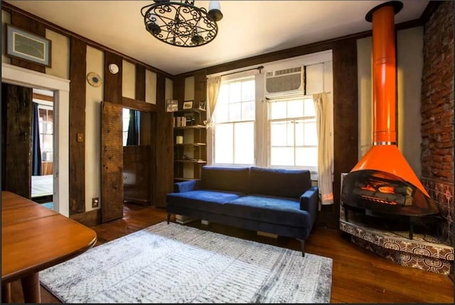 sitting room with a wood stove, a wall mounted air conditioner, and dark hardwood / wood-style floors