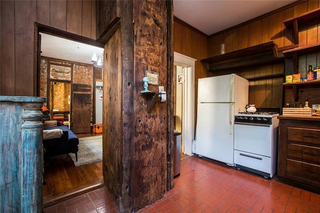 kitchen featuring white appliances, ornamental molding, and wooden walls