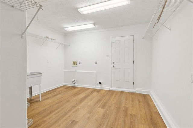 clothes washing area featuring crown molding, hookup for a washing machine, wood-type flooring, and a textured ceiling