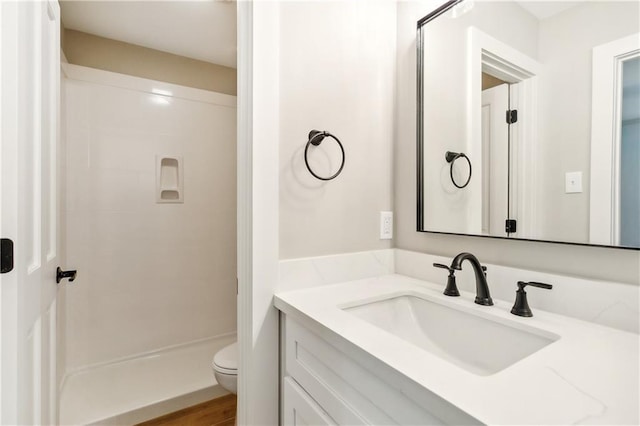 bathroom featuring hardwood / wood-style flooring, a shower, vanity, and toilet