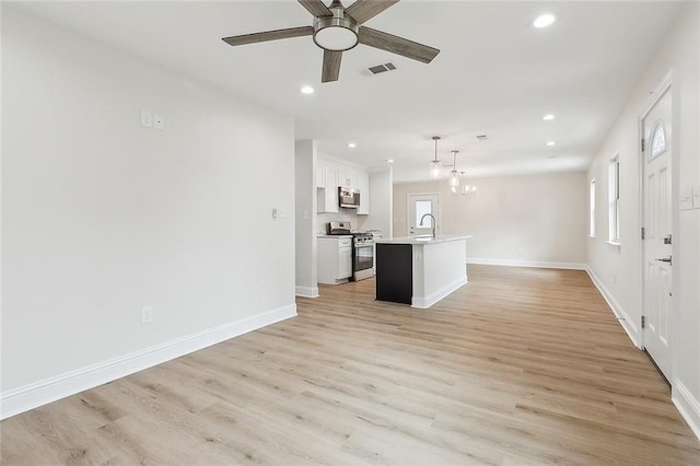 kitchen with hanging light fixtures, light hardwood / wood-style flooring, an island with sink, white cabinetry, and stainless steel appliances