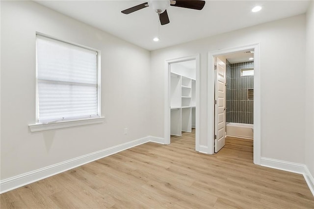 unfurnished bedroom with a walk in closet, a closet, light hardwood / wood-style flooring, and ceiling fan