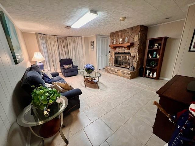 tiled living room featuring a stone fireplace, wooden walls, and a textured ceiling