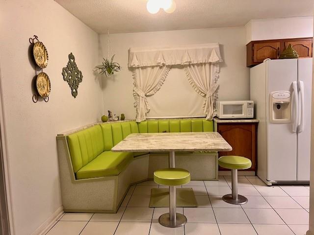 living area with breakfast area, a textured ceiling, and light tile patterned floors