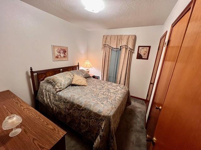 bedroom featuring a closet, a textured ceiling, and dark colored carpet