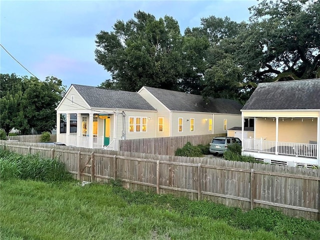 exterior space with a fenced front yard and roof with shingles