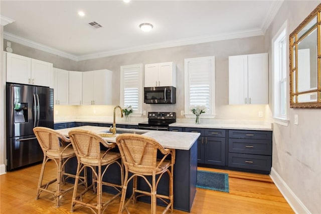 kitchen with appliances with stainless steel finishes, a sink, visible vents, and white cabinets