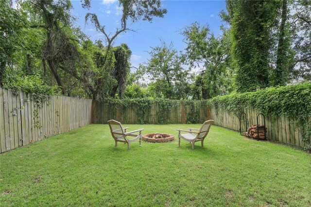 back of house with a yard and an outdoor fire pit