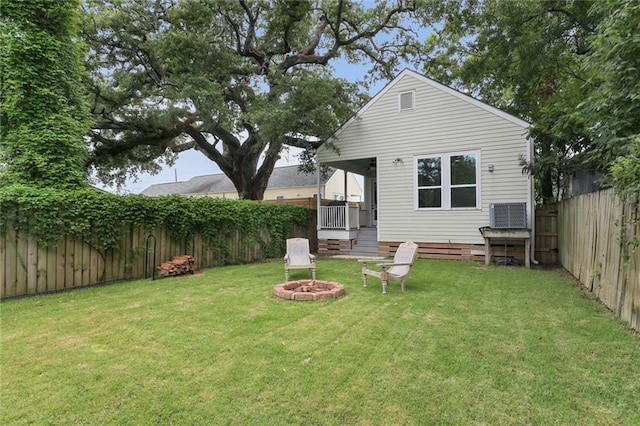 rear view of house with an outdoor fire pit, a lawn, and a fenced backyard