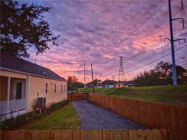 yard at dusk featuring a gate, central AC, and fence