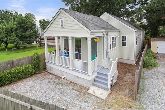 view of front of house featuring a shingled roof, fence private yard, covered porch, and a front yard