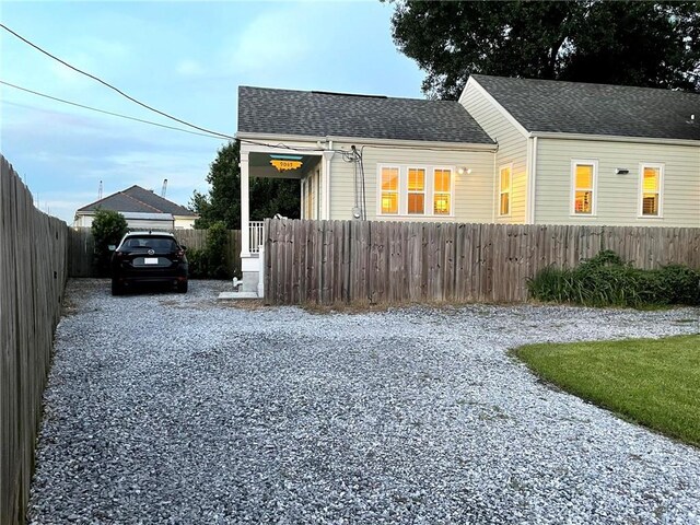 view of front of house featuring gravel driveway, a fenced front yard, and roof with shingles