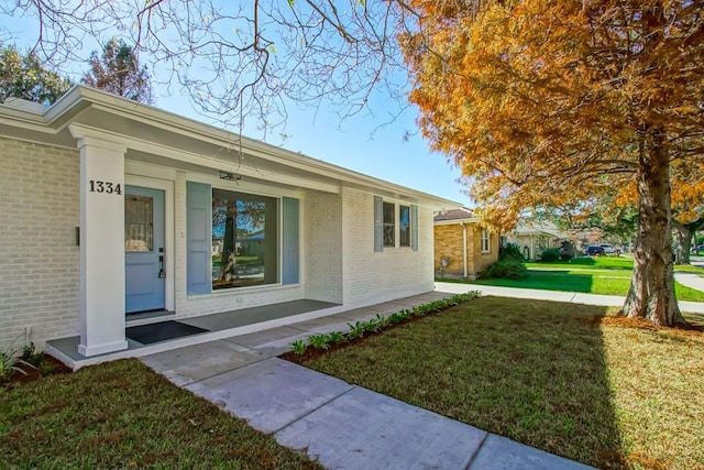 entrance to property with covered porch and a yard