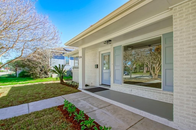 entrance to property with a lawn and a porch