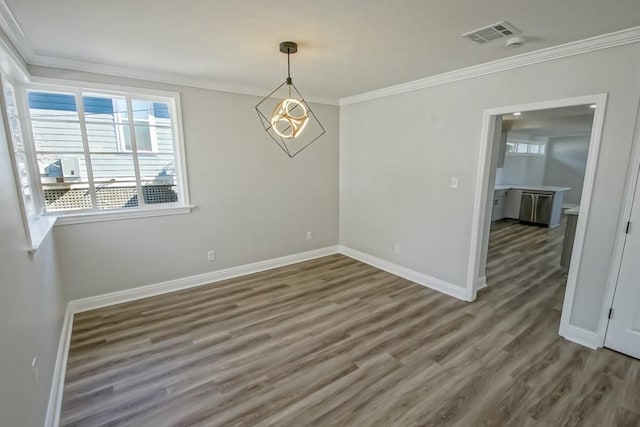 spare room featuring a chandelier, dark wood-type flooring, and ornamental molding