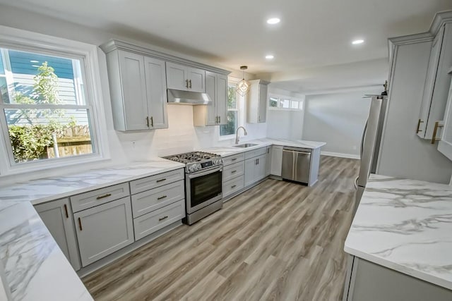 kitchen featuring sink, hanging light fixtures, gray cabinets, decorative backsplash, and appliances with stainless steel finishes