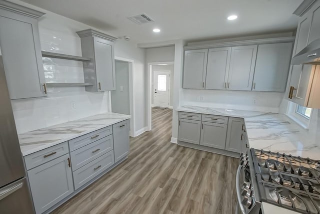 kitchen with light stone countertops, gray cabinets, and stainless steel range with gas cooktop