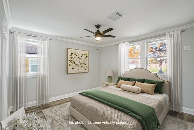 bedroom featuring multiple windows, hardwood / wood-style flooring, ceiling fan, and crown molding