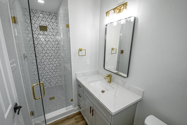 bathroom with hardwood / wood-style flooring, vanity, toilet, and walk in shower