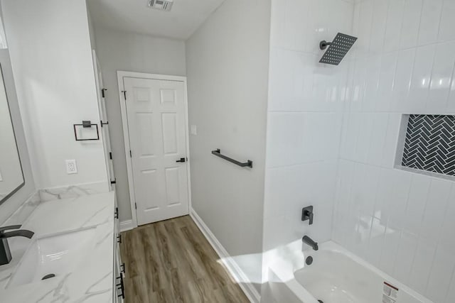 bathroom featuring hardwood / wood-style flooring, vanity, and tiled shower / bath