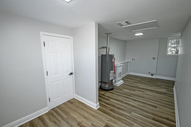 laundry room with water heater and dark hardwood / wood-style flooring