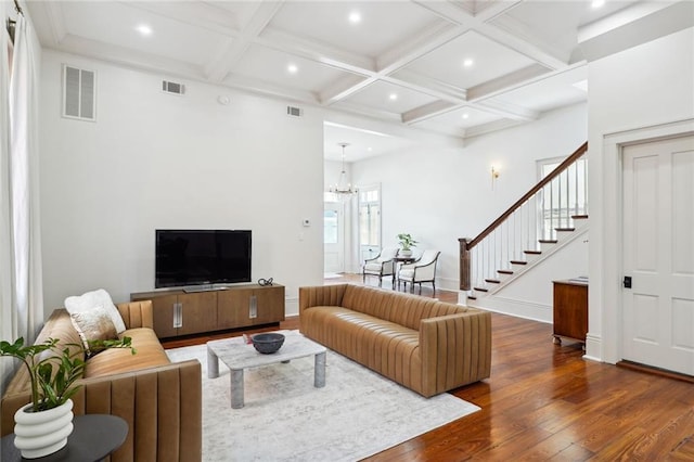 living room featuring beamed ceiling, coffered ceiling, dark wood-type flooring, and an inviting chandelier