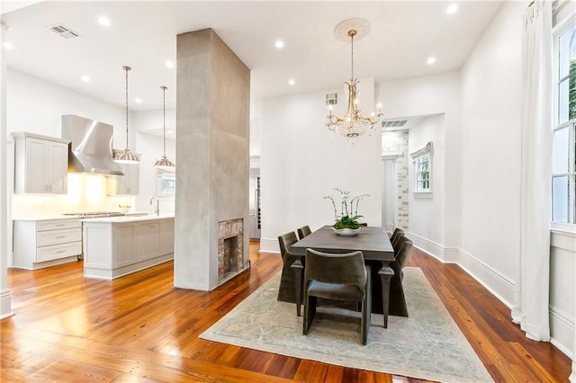 dining space with a chandelier, sink, and light hardwood / wood-style flooring