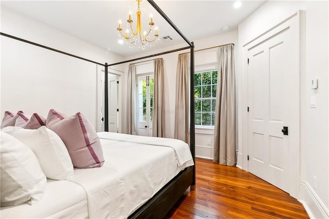 bedroom with dark wood-type flooring and a notable chandelier