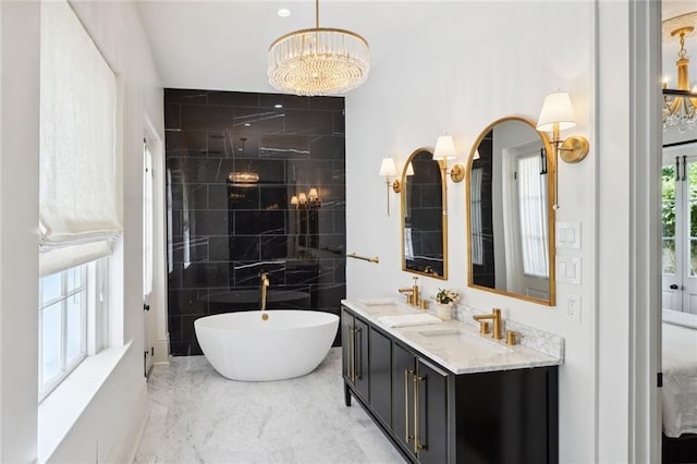 bathroom with a chandelier, vanity, and a bathing tub