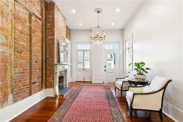 foyer with dark hardwood / wood-style floors, a tile fireplace, and a chandelier