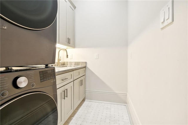 washroom featuring cabinets, stacked washer and clothes dryer, and sink